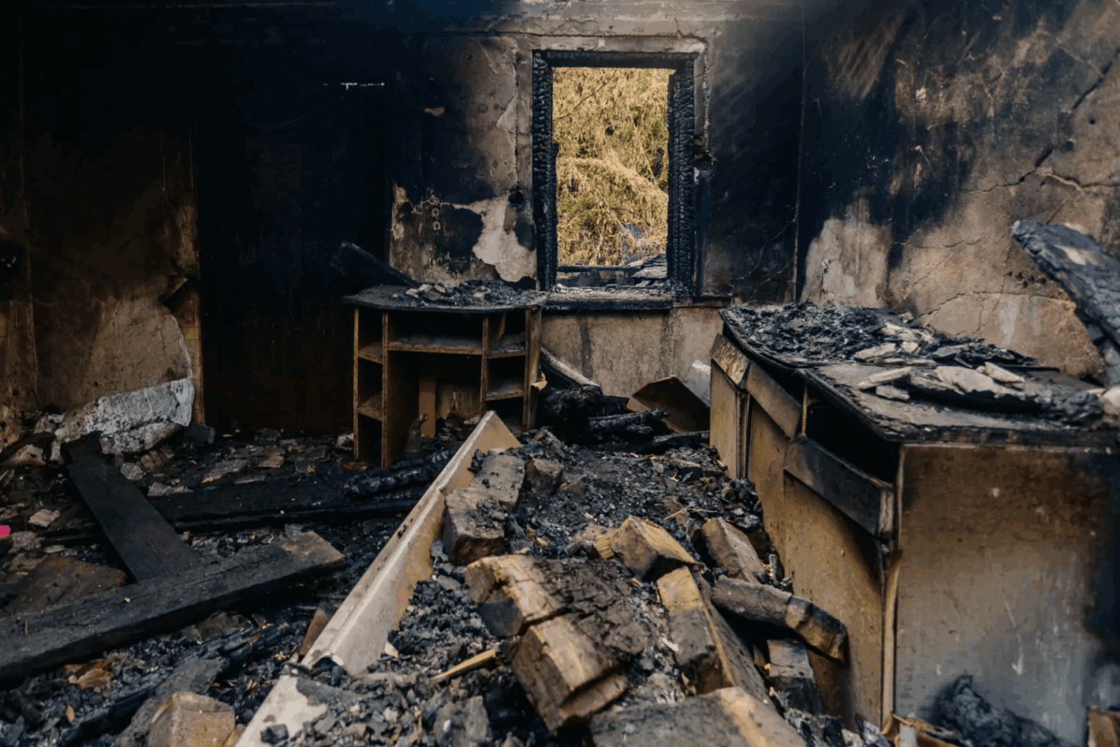 Burned room with charred debris and window.